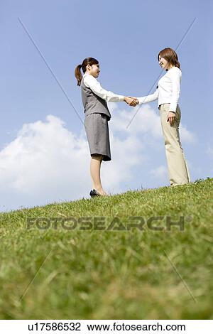 Stock Image - Businesswomen shaking hands. Fotosearch