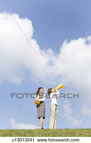 Stock Image - Businesswomen shouting into megaphone. Fotosearch