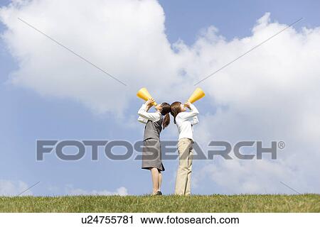 Stock Image - Businesswomen shouting into megaphone. Fotosearch