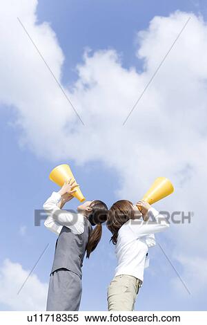 Stock Photography - Businesswomen shouting into megaphone. Fotosearch