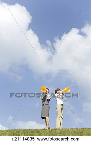 Stock Photography - Businesswomen shouting into megaphone. Fotosearch