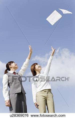 Stock Photograph - Businesswomen throwing documents in air. Fotosearch