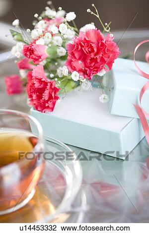 Stock Image - Carnations with a gift box and a cup of tea. Fotosearch