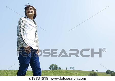 Cheerful man standing on grass View Large Photo Image Stock Photo - Cheerful man standing on grass. Fotosearch