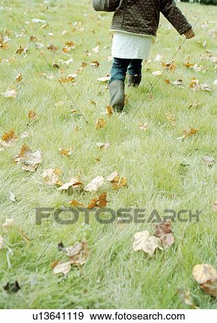 Stock Photo - Child running in grass with fallen leaves. Fotosearch