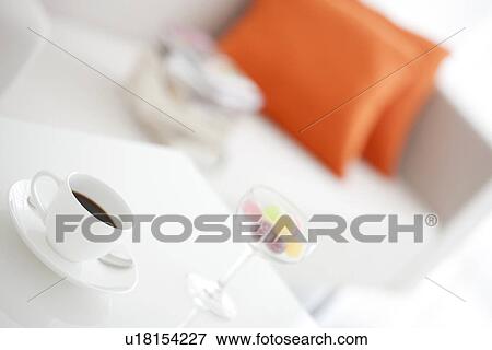 Stock Photo - Coffee and a glass of candy on a living room table. Fotosearch
