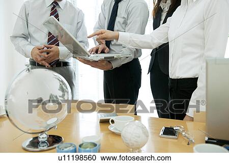 Stock Image - Colleagues looking at laptop. Fotosearch
