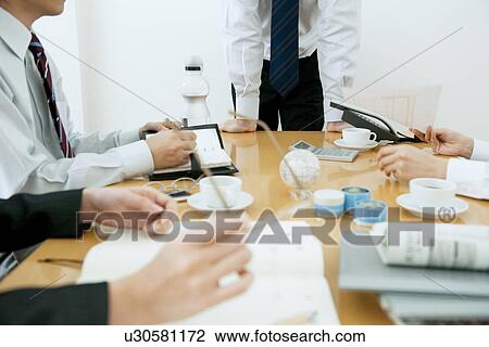Stock Image - Colleagues working at desk in office. Fotosearch
