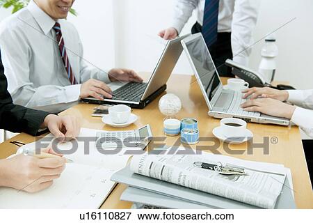 Stock Photo - Colleagues working at desk in office. Fotosearch