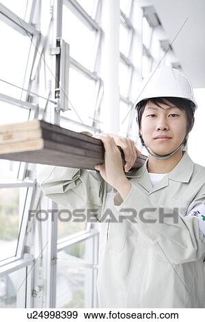Stock Photo - Construction worker carrying wooden planks. Fotosearch