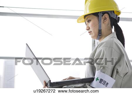 Stock Image - Construction worker using laptop. Fotosearch