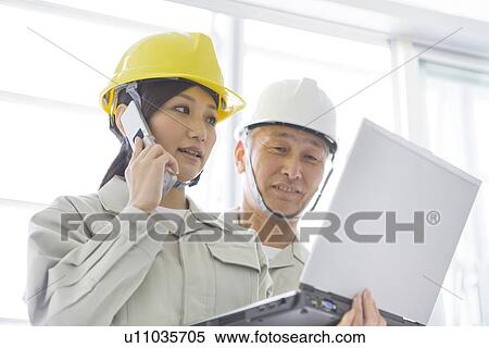 Stock Photography - Construction workers with laptop and mobile phone. Fotosearch