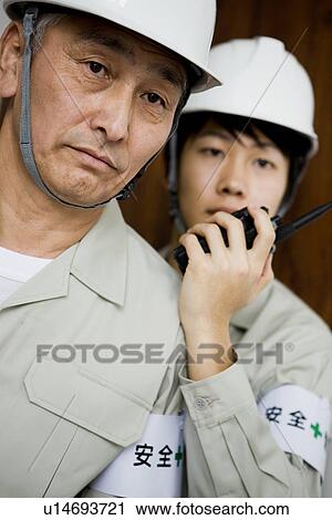 Stock Image - Construction workers with walkie-talkie. Fotosearch
