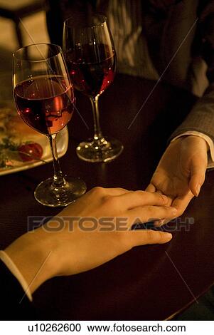 Stock Image - Couple holding hands over a table. Fotosearch