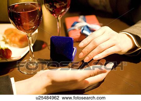 Stock Image - Couple holding hands with a jewelry box on the table. Fotosearch
