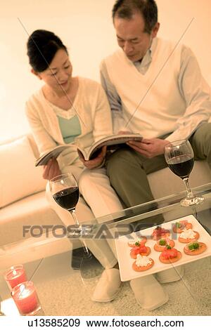 Couple looking through a magazine View Large Photo Image Stock Photo - Couple looking through a magazine. Fotosearch
