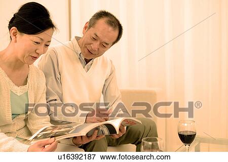 Couple looking through a magazine View Large Photo Image Stock Photo - Couple looking through a magazine. Fotosearch