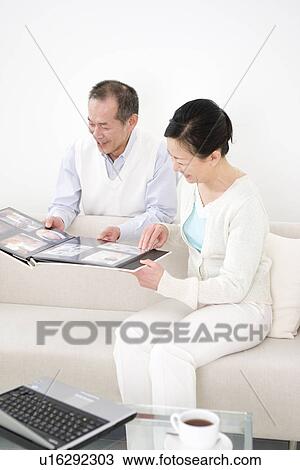 Couple looking through photo albums View Large Photo Image Stock Image - Couple looking through photo albums. Fotosearch