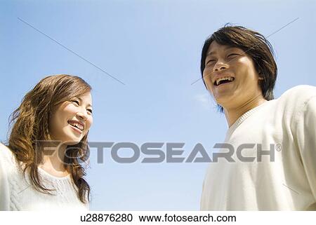 Stock Image - Couple standing under a blue sky. Fotosearch