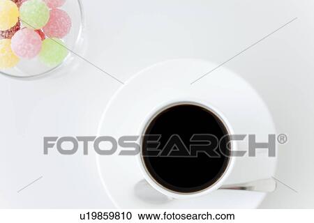 Stock Image - Cup of coffee and a glass of candy. Fotosearch