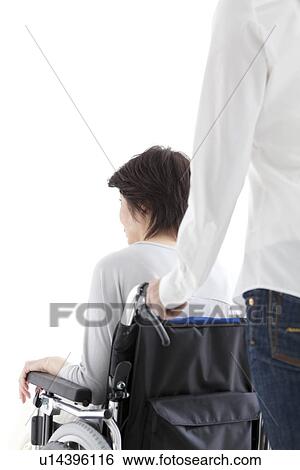 Stock Photograph - Daughter pushing her mother in a wheelchair. Fotosearch