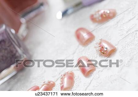 Stock Image - Decorated false nails with nail polish bottles. Fotosearch