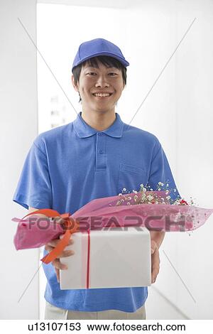 Delivery man delivering a bouquet and a present View Large Photo Image Stock Image - Delivery man delivering a bouquet and a present. Fotosearch