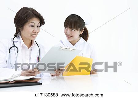 Doctor and nurse examining file View Large Photo Image Stock Photo - Doctor and nurse examining file. Fotosearch