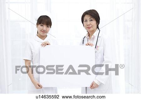 Stock Image - Doctor and nurse with blank message board. Fotosearch