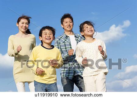Stock Image - Family of four running against a blue sky. Fotosearch