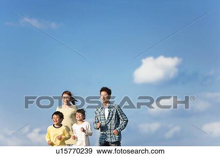 Stock Photo - Family of four running against a blue sky. Fotosearch