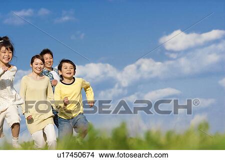 Family of four running at the park against a blue sky View Large Photo Image Picture - Family of four running at the park against a blue sky. Fotosearch