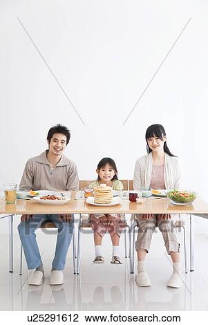 Stock Image - Father, mother and daughter sitting at breakfast table together. Fotosearch