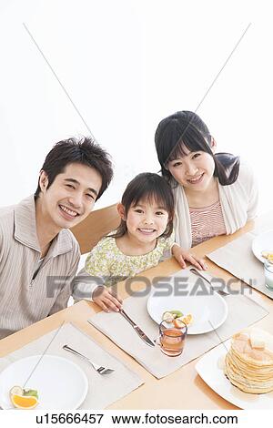 Stock Photo - Father, mother and daughter sitting at breakfast table together. Fotosearch