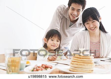 Stock Photography - Father, mother and daughter sitting at breakfast table together. Fotosearch