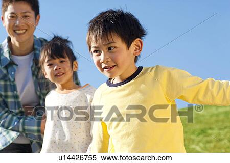 Stock Photography - Father with his young son and daughter at the park against a clear blue sky. Fotosearch