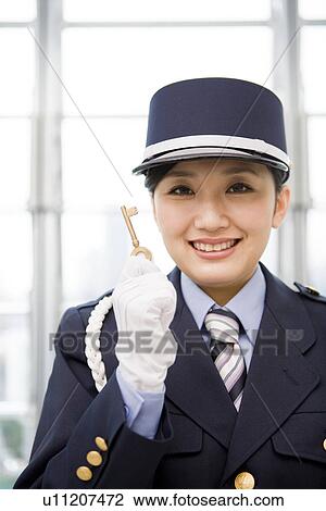 Stock Image - Female guard holding a key. Fotosearch