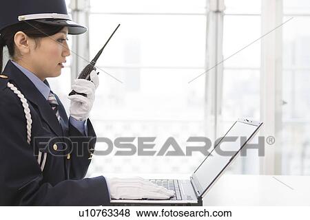 Female guard using laptop and talking on walkie-talkie View Large Photo Image Stock Photo - Female guard using laptop and talking on walkie-talkie. Fotosearch