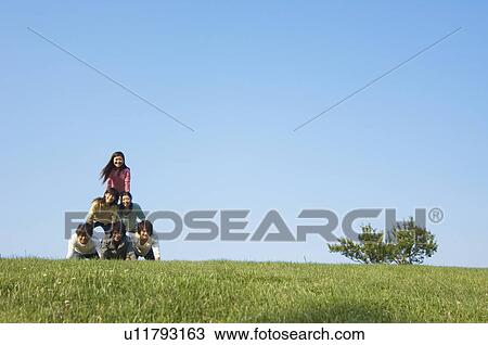 Stock Image - Five people making human pyramid. Fotosearch
