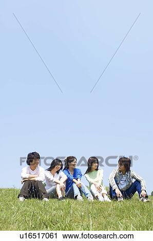 Stock Image - Five young people sitting on grass. Fotosearch