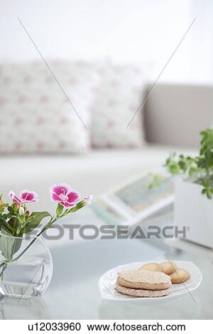 Stock Image - Flowers and cookies on a living room table. Fotosearch