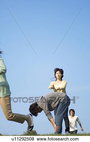 Stock Photo - Four people playing leapfrog on grass. Fotosearch