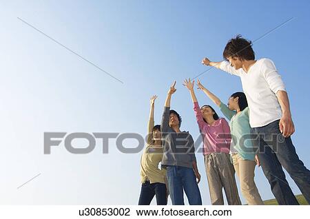 Friends gesturing towards the sky View Large Photo Image Stock Image - Friends gesturing towards the sky. Fotosearch