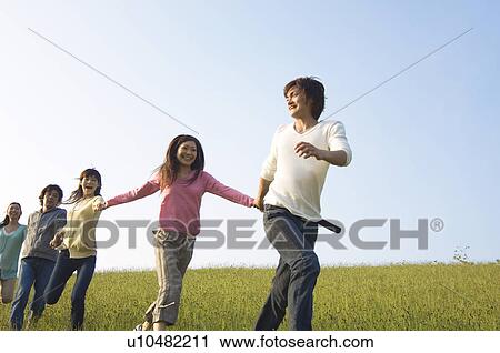 Friends running hand in hand through a field View Large Photo Image Stock Image - Friends running hand in hand through a field. Fotosearch