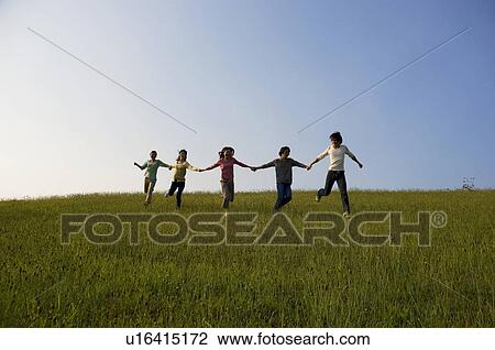 Friends running hand in hand through a field View Large Photo Image Stock Image - Friends running hand in hand through a field. Fotosearch