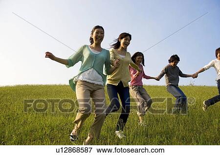 Friends running hand in hand through a field View Large Photo Image Stock Photo - Friends running hand in hand through a field. Fotosearch