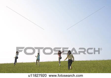 Stock Image - Friends running through a field. Fotosearch