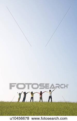 Friends standing hand in hand in a field View Large Photo Image Stock Photo - Friends standing hand in hand in a field. Fotosearch
