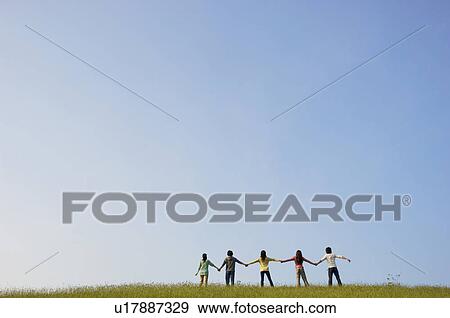 Friends standing hand in hand in a field View Large Photo Image Stock Photo - Friends standing hand in hand in a field. Fotosearch
