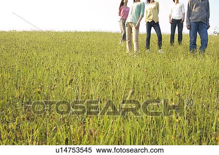 Stock Photography - Friends standing in a field. Fotosearch